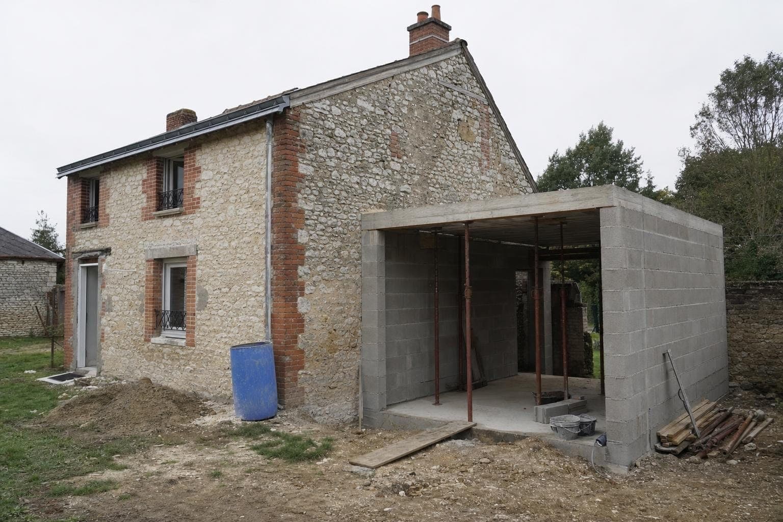 Extension en blocs béton accolée à une maison ancienne en pierre de craie et brique